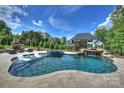 Resort-style pool with waterfall feature, sun loungers, and outdoor fireplace for ultimate relaxation at 2004 Garden View Ln, Weddington, NC 28104