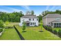 Aerial view of a fenced backyard, featuring a screened patio, lush lawn, and solar panels on the home at 6416 Willow Pin Ln, Huntersville, NC 28078