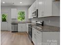 Bright kitchen featuring stainless steel appliances, granite counters and white cabinets at 706 Live Oak St, Shelby, NC 28150
