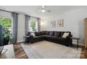 Cozy living room with plush sectional sofa, large windows, ceiling fan, and stylish decor at 8381 Chatsworth Dr, Indian Land, SC 29707