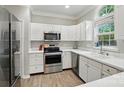 Well-lit kitchen featuring white cabinets, stainless steel appliances, quartz countertops, and hardwood flooring at 8744 Barrister Way, Charlotte, NC 28216