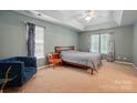 Spacious primary bedroom with tray ceiling, large windows, and neutral carpet flooring at 8744 Barrister Way, Charlotte, NC 28216