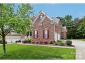 Beautiful brick home with lush green lawn, colorful flowerbeds, and a two car garage at 9034 Kensington Forest Dr, Harrisburg, NC 28075