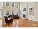 Spacious living room with soaring ceilings, a fireplace, built-in shelving, and hardwood floors at 9034 Kensington Forest Dr, Harrisburg, NC 28075