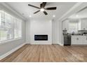 Open concept living area with modern fireplace, ceiling fan, light gray paint, and wood flooring at 1067 Winchester Dr, Rock Hill, SC 29730