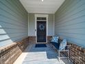 Inviting front porch with a bench, decorative pillows, rug, and a wreath on the front door at 1456 Augustus Beamon Dr, Indian Trail, NC 28079