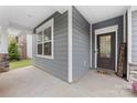 Inviting covered front porch with stylish gray siding, a modern front door, and stone accents at 15630 Oleander Dr, Charlotte, NC 28278