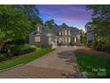 Elegant home featuring a gray facade, well-manicured landscaping, and a spacious driveway leading to an attached garage at 17938 John Connor Rd, Cornelius, NC 28031