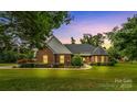 Inviting brick home with manicured lawn and garden beds, offering a warm, serene ambiance at twilight at 1825 Smyre Farm Rd, Newton, NC 28658