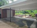 Covered parking area with brick support columns and view of landscaped backyard at 520 Crestview Dr, Albemarle, NC 28001