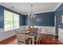 Traditional dining room featuring chair-rail detail, blue walls, hardwood floors, and a chandelier over the dining table at 6309 Crosshall Pl, Waxhaw, NC 28173