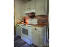 Rustic kitchen features white appliances, cabinetry, and a brick accent wall above the oven at 850 Meadowbend Dr, York, SC 29745