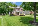 Inviting two-story home with brick facade, red shutters, and lush green lawn at 10322 Stoneykirk Ln, Charlotte, NC 28269