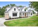 Beautiful two-story white farmhouse with a black roof, covered porch, and a two-car garage at 104 Arbor Dr, Waxhaw, NC 28173