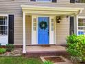 Inviting front entrance with a bright blue door, a decorative wreath, and manicured landscaping at 11718 Battery Pl, Charlotte, NC 28273