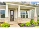 Inviting front porch with brick accents, sturdy columns, and manicured landscaping at 13702 Tranquil Day Dr, Matthews, NC 28105