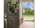 View of the front door with decorative wreath, digital lock, and a peek at lush greenery nearby at 1813 Shelbourne Way, Fort Mill, SC 29707