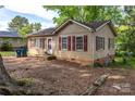 Tan single-story house with red shutters and partial brick foundation at 208 N School St, Mount Gilead, NC 27306
