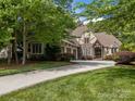 Beautiful home with lush green lawn, manicured landscaping, a large driveway, and classic Tudor architecture at 104 Golden Bell Ct, Mooresville, NC 28117