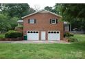 Three car garage with white doors, brick exterior, and an ample driveway at 116 Lanes End Rd, Locust, NC 28097