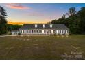 Charming one-story home featuring a welcoming front porch and lush, sprawling lawn at sunset at 1230 Long Creek Ln, Salisbury, NC 28146