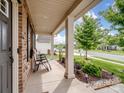 Inviting front porch with brick accents, a manicured garden, and comfortable chairs for relaxing outdoors at 2178 Stone Pile Sw Dr, Concord, NC 28025
