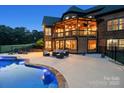 Outdoor living space with covered porch, lounge furniture, and sparkling pool at dusk at 270 Sandhills Ct, Mooresville, NC 28115