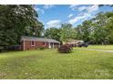 Brick ranch home situated on a large lot with a long gravel driveway and mature trees at 4915 Galax Dr, Charlotte, NC 28213