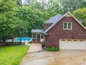 Exterior view of a brick home with a pool, screened porch, and a two-car garage at 8527 Foxbridge Dr, Matthews, NC 28104