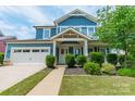 Attractive two-story blue home with a covered porch, manicured landscaping, and a two-car garage at 12107 Grey Partridge Dr, Charlotte, NC 28278