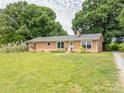 Well-kept brick home features a large front lawn, mature trees, and a welcoming entrance at 1325 Marshville Olive Branch Rd, Marshville, NC 28103