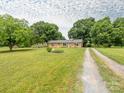 Attractive brick home with a sprawling lawn, mature trees, and a long gravel driveway at 1325 Marshville Olive Branch Rd, Marshville, NC 28103