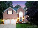 Exterior view of brick home with two-car garage and manicured lawn at dusk at 15301 Marsh Field Ct, Huntersville, NC 28078