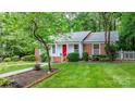 Traditional brick home with a red door and white trim is set amidst a lush green lawn and mature trees at 220 Pinehurst Ln, Newton, NC 28658