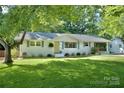 Charming white brick home with a well-manicured lawn, mature trees, and a welcoming yellow front door at 3549 Woodleaf Rd, Charlotte, NC 28205