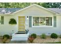 Close-up of a bright, freshly painted white brick home with an attractive, contrasting yellow front door at 3549 Woodleaf Rd, Charlotte, NC 28205