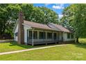 Exterior view featuring a covered porch, brick chimney, and landscaped surroundings at 5200 Winding Ln, Indian Trail, NC 28079