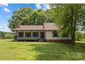 Charming front exterior featuring a covered porch and well-maintained yard with mature trees at 5200 Winding Ln, Indian Trail, NC 28079