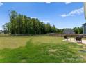 Large, well-maintained backyard with green grass, a wooden fence, mature trees, and a small patio area at 110 Browband St, Troutman, NC 28166