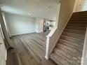 Bright living room featuring stairs, with wood-look flooring, and an open floorplan to the kitchen at 110 Browband St, Troutman, NC 28166