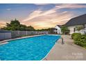 Sparkling in-ground pool with a nearby gazebo, enclosed by a white picket fence at 129 Renaissance Pl, Statesville, NC 28625