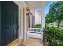 Cozy front porch featuring a classic black door, white bench, and wrought iron railing at 138 Montibello Dr, Mooresville, NC 28117