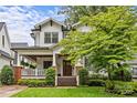 Inviting two-story home boasts white siding, black trim, a covered porch, and mature trees in the front yard at 2615 Chesterfield Ave, Charlotte, NC 28205