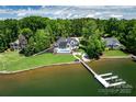 Expansive lakefront property with a modern home, pool, lush landscaping, and private boat dock at 301 Riverwood Rd, Mooresville, NC 28117