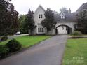Elegant home featuring a connecting portico to the garage and mature trees lining the driveway at 450 Greywalls Ln, Iron Station, NC 28080