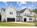 Beautiful two-story white farmhouse with a black garage door and pristine landscaping on a sunny day at 4530 Tournette Dr # 18, Indian Land, SC 29707