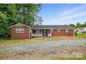 A quaint single story brick home with a white lattice porch and gravel driveway in the front at 800 Old Little Rock Rd, Charlotte, NC 28214