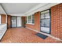 Covered front porch featuring tile flooring, brick walls, and black iron security door and white railing at 800 Old Little Rock Rd, Charlotte, NC 28214