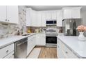 Bright kitchen featuring white cabinets, stainless steel appliances, and marble backsplash at 1066 Mclain Rd # 14, Kannapolis, NC 28083