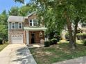 Attractive brick and stone home with a green roof, showcasing a neat front yard and mature tree at 13913 Pinyon Pine Ln, Charlotte, NC 28215